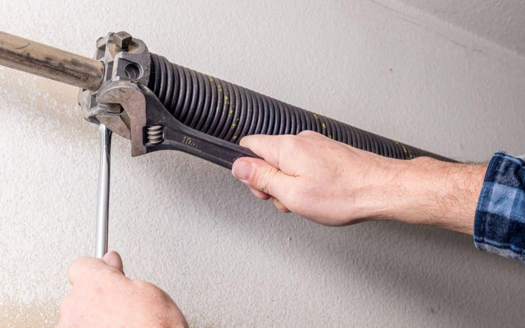 A man who learned how to replace garage door springs performs this maintenance task.
